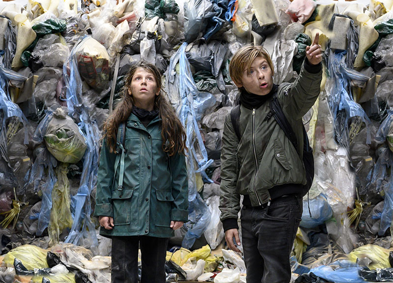 Die Kinder stehen vor einem Riesenberg von Mülltüten