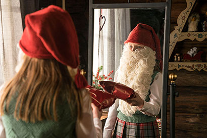 Lucia steht vor dem Spiegel und hält sich einen Weihnachtsmannbart vor das Gesicht