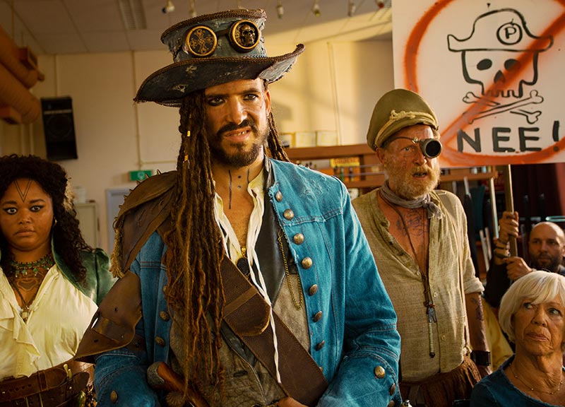 Die Piraten auf der Bürgerversammlung, im Publikum hält jemand ein Schild mit einem durchgestrichenen Piraten-Totenkopf und dem Wort „Nee!“ hoch