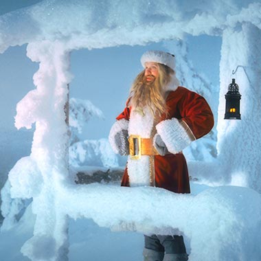 Der Weihnachtsmann steht auf einem verschneiten Balkon