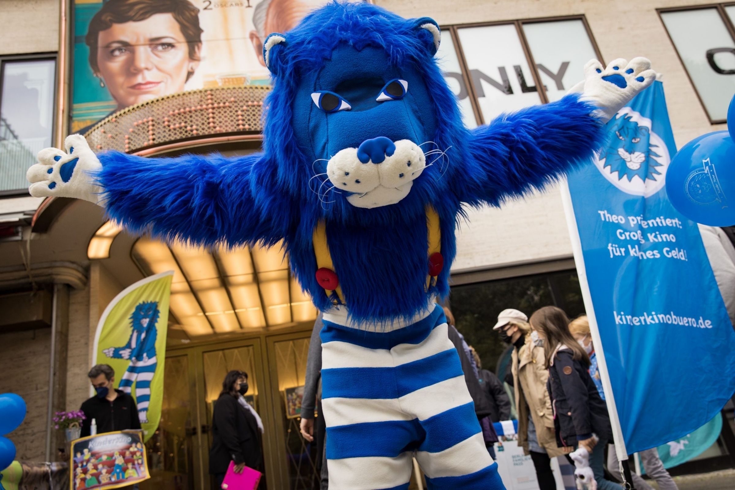 Theo steht mit ausgebreiteten Armen vor dem Eingang der Astor Film Lounge