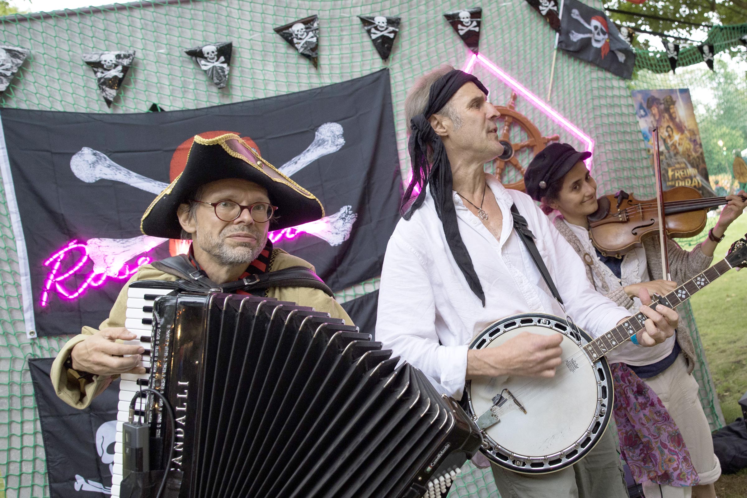 Musikerin und Musiker mit Akkordeon, Banjo und Geige in Piratenkleidung