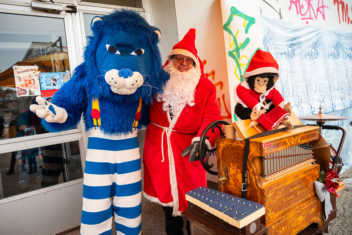 Theo mit einem Weihnachtsmann neben einer Drehorgel auf der ein Stofftieraffe im Weihnachtsmann-Kostüm sitzt
