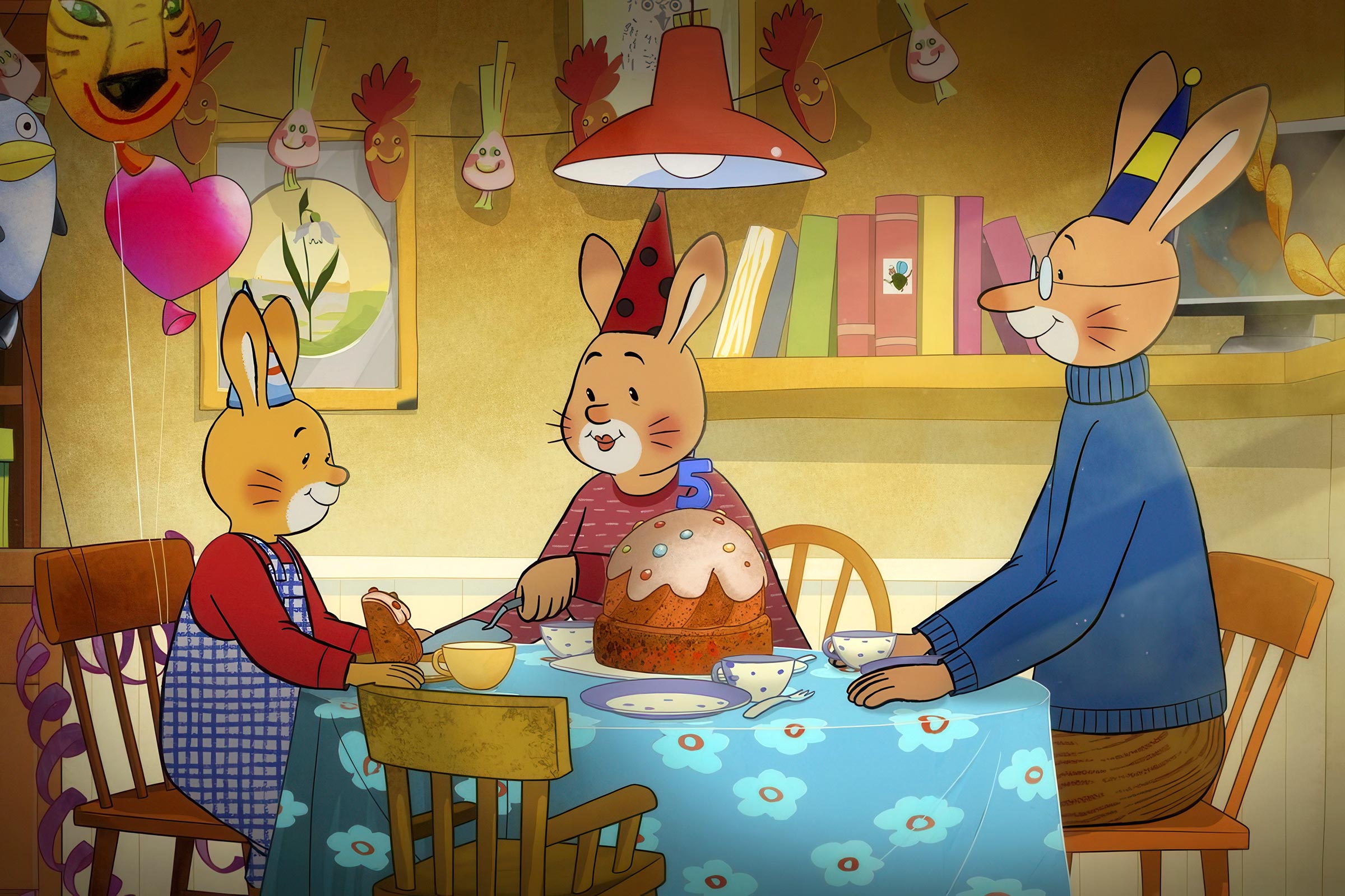 Karlchen sitzt mit seinen Eltern am Tisch, auf dem ein Kuchen mit einer 5 steht.