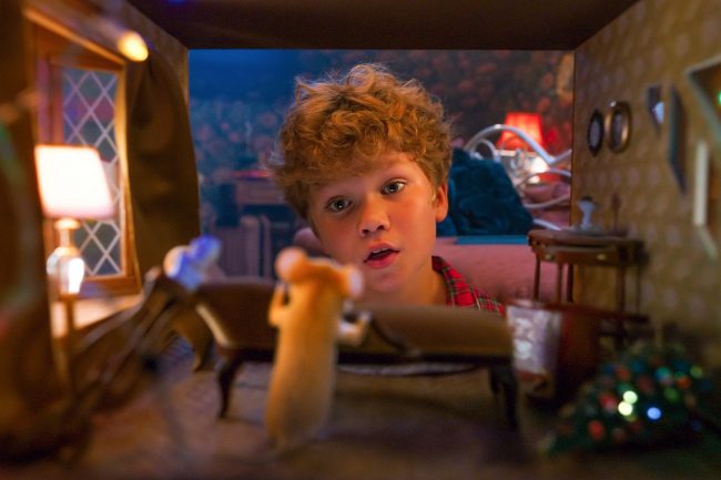 Der Junge Mikkel entdeckt die Maus Lea in ihrem kleinen Wohnzimmer und sieht sie auf Augenhöhe an